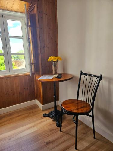a table with a chair and a table with a vase of flowers at Alcamim Guesthouse in Elvas