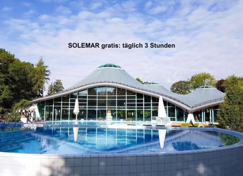 a building with a swimming pool in front of it at Haus Ahorn Ferienwohnung in Bad Dürrheim