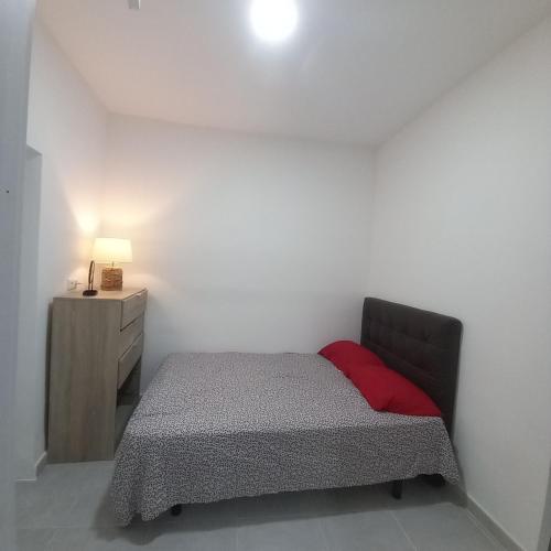 - une petite chambre avec un lit et un oreiller rouge dans l'établissement Clavelina Economy Room calle Julio Antonio, à Alicante