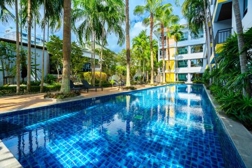 a swimming pool with palm trees and a building at Anchan Boutique Hotel in Chalong 