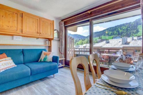 a living room with a blue couch and a table with chairs at Sunny central studio in Morzine