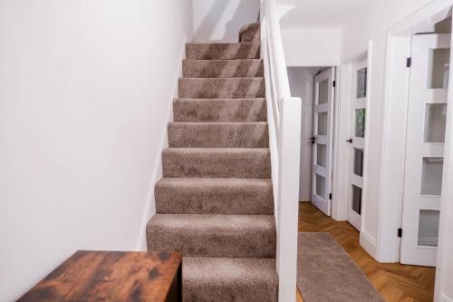 a staircase in a house with a wooden table at Exquisite 3BD Nordic Retreat with Parking in Timperley