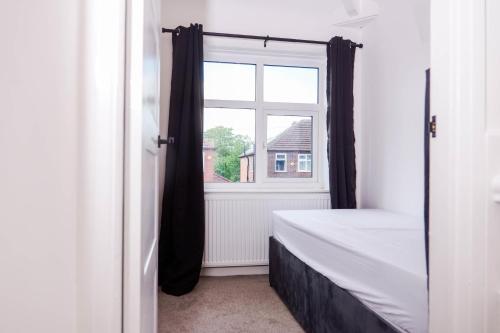 a bedroom with a bed and a window at Exquisite 3BD Nordic Retreat with Parking in Timperley