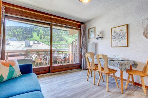 a living room with a table and chairs and a balcony at Sunny central studio in Morzine