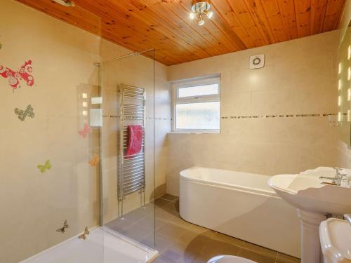 a bathroom with a tub shower and a sink at 4 Bed in Duddon Valley 89418 in Ulpha