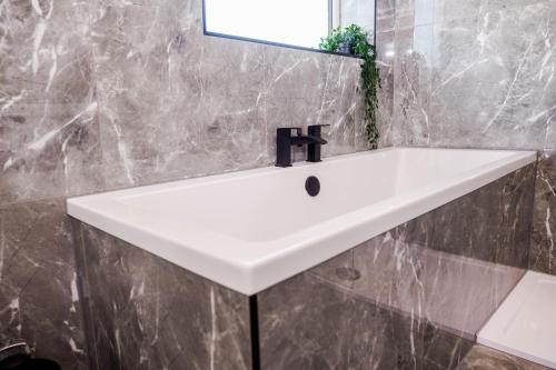 a white sink in a bathroom with a mirror at Exquisite 3BD Nordic Retreat with Parking in Timperley