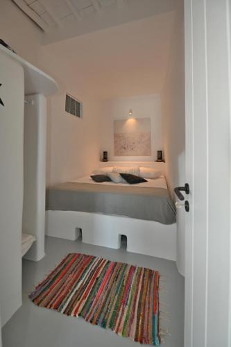 a bedroom with a bed and a rug at Kariki Blue Triantaros-Tinos in Triandáros