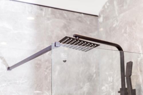 a glass shower with a black handle in a bathroom at Exquisite 3BD Nordic Retreat with Parking in Timperley