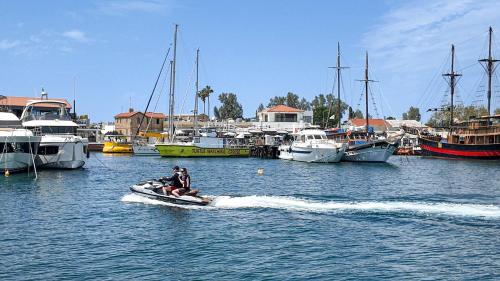 two people on a jet ski in the water with boats at Villa Talya in Peyia