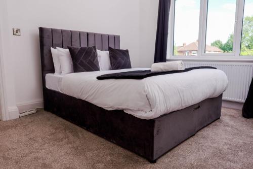 a bedroom with a large bed with white sheets and pillows at Exquisite 3BD Nordic Retreat with Parking in Timperley