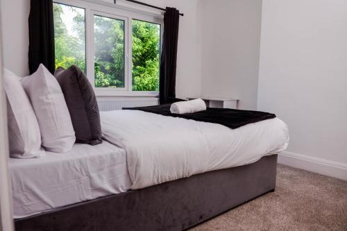 a bedroom with a large bed with a window at Exquisite 3BD Nordic Retreat with Parking in Timperley