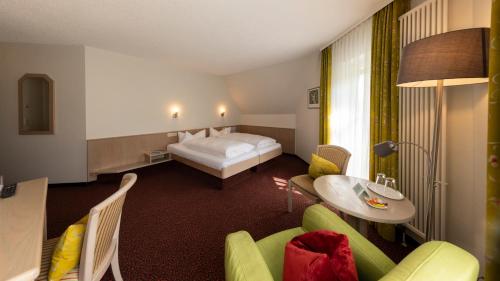 a hotel room with a bed and a table and chairs at Castell Hotel & Restaurant in Leinsweiler