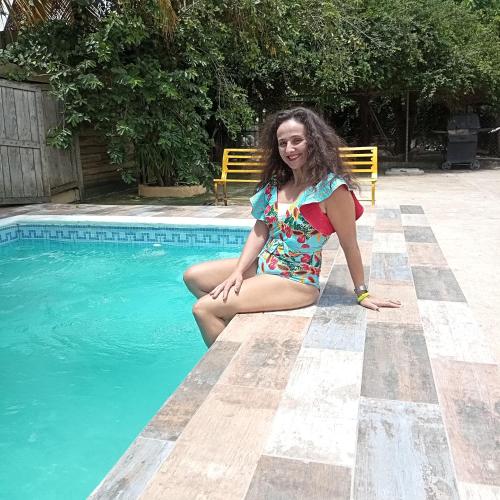 a woman in a bathing suit sitting next to a swimming pool at Paraiso Hortensia Ecolodge in Santiago de los Caballeros