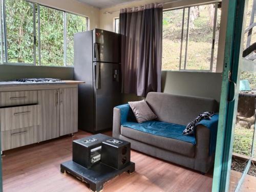 ein Wohnzimmer mit Couch und Kühlschrank in der Unterkunft Tiny House Serendipia - Caserío El Puente -Villeta in Villeta