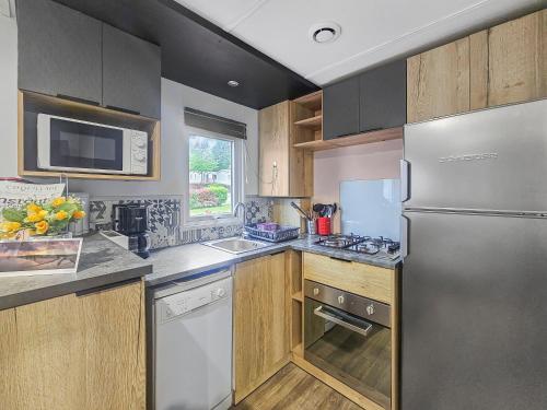 une cuisine avec un réfrigérateur en acier inoxydable et des armoires en bois dans l'établissement un air de vacances, à Litteau