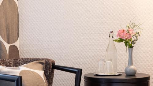 a table with a vase of flowers and a chair at Castell Hotel & Restaurant in Leinsweiler