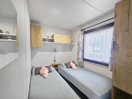 deux lits dans une chambre avec une fenêtre dans l'établissement un air de vacances, à Litteau