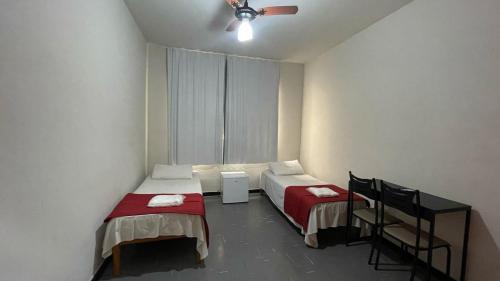 a room with two beds and a ceiling fan at Hotel Aquarius in Coronel Fabriciano