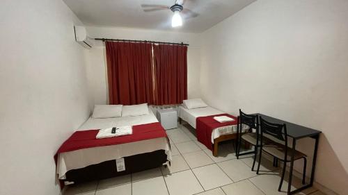 a room with two beds and a table and a window at Hotel Aquarius in Coronel Fabriciano