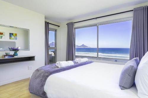 a bedroom with a large bed and a large window at Sea Spray B306 in Bloubergstrand