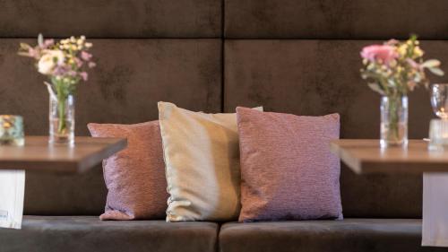 a couch with three pillows and two tables with flowers at Castell Hotel & Restaurant in Leinsweiler