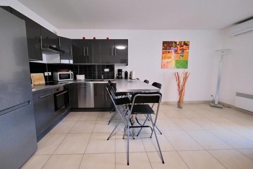 a kitchen with black cabinets and a table and chairs at Magnifique T3 proche de la plage in Calvi