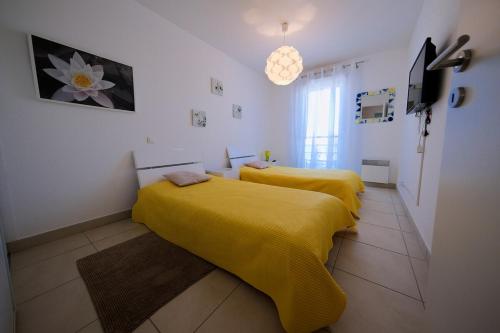 two beds in a room with yellow sheets at Magnifique T3 proche de la plage in Calvi