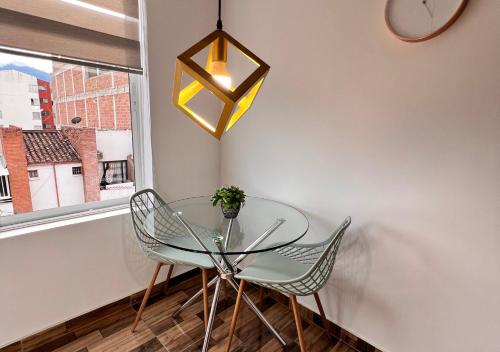 a glass table and chairs in a room with a window at PARK 66 Apartaestudios in Cali