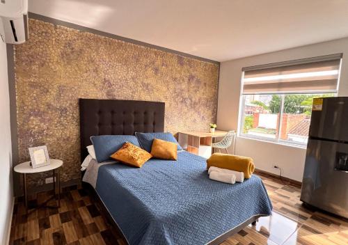 a bedroom with a bed with blue sheets and yellow pillows at PARK 66 Apartaestudios in Cali