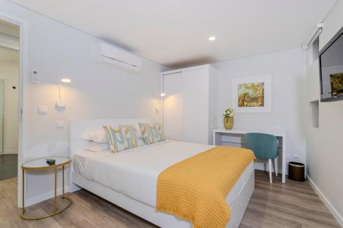 a white bedroom with a bed and a desk at Casa do Senhor do Colégio in Ponta Delgada
