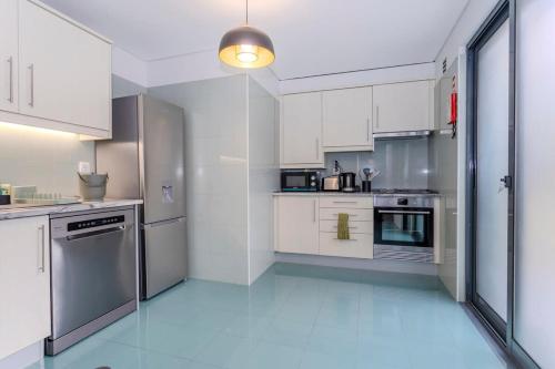 una gran cocina blanca con armarios y electrodomésticos blancos en GuestReady - Casa do Senhor do Colégio, en Ponta Delgada