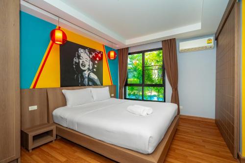 a bedroom with a bed and a painting on the wall at Anchan Boutique Hotel in Chalong 