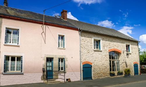 an old brick building with blue doors on a street at Gîte chezmadlou in Colondannes