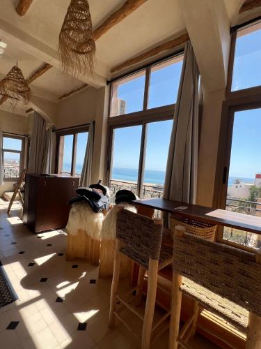 a room with a table and chairs and windows at SurfAppart Morocco in Tamraght Ouzdar