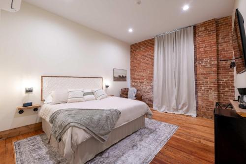 Un dormitorio con una cama grande y una pared de ladrillo. en Courtyard King - Room 3, en Versailles
