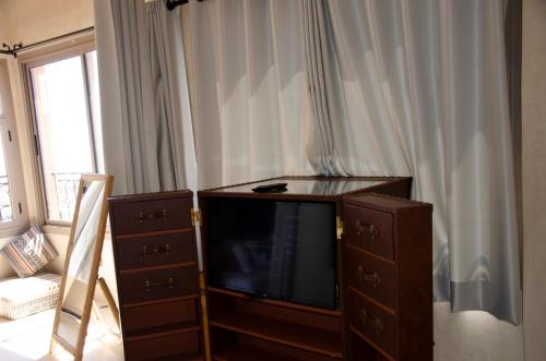 a living room with a flat screen tv and a dresser at SurfAppart Morocco in Tamraght Ouzdar
