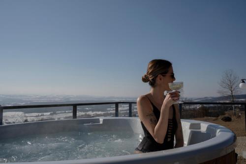 a woman sitting in a hot tub with a drink at Gorczański Lux Chalet in Szlembark