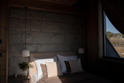 a bedroom with a bed with white pillows and a window at Gorczański Lux Chalet in Szlembark