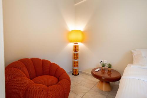 a bedroom with a red chair and a lamp at Villy's Comfort Zone Apartments in Kalamata