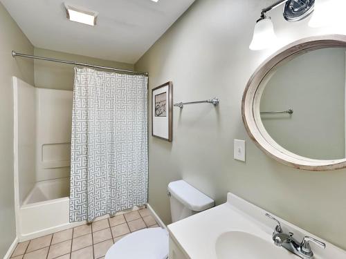 a bathroom with a toilet and a sink and a mirror at Latitude Adjustment A in Tybee Island