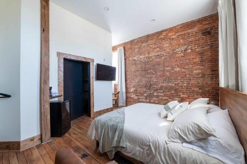 Un dormitorio con una pared de ladrillo y una cama. en ADA Suite - Room 6, en Versailles