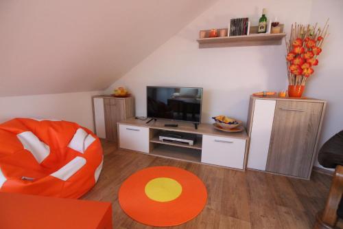 un salon avec une chaise orange et une télévision dans l'établissement Orange Loft Apartment, à Kájov