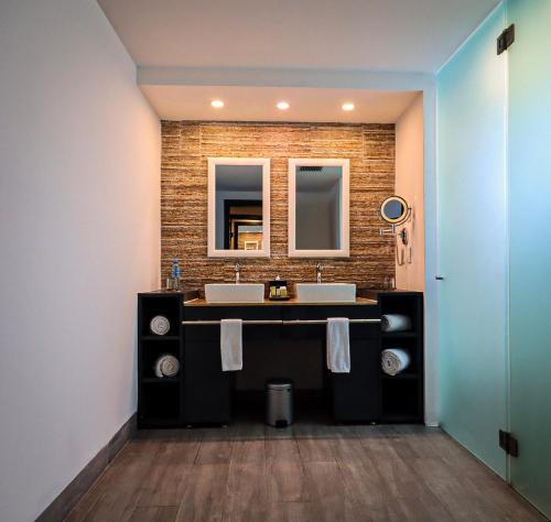 a bathroom with two sinks and a brick wall at The Fives Beach Hotel & Residences - All Senses Inclusive in Playa del Carmen