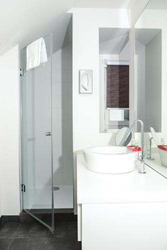 a white bathroom with a sink and a shower at Hôtel Ar Iniz in Saint Malo