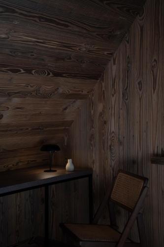 a lamp and a chair in a room with wooden walls at Gorczański Lux Chalet in Szlembark