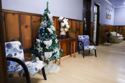 a christmas tree in a room with two chairs at Pousada Vista do Lago: Lazer e família em Gramado! in Gramado