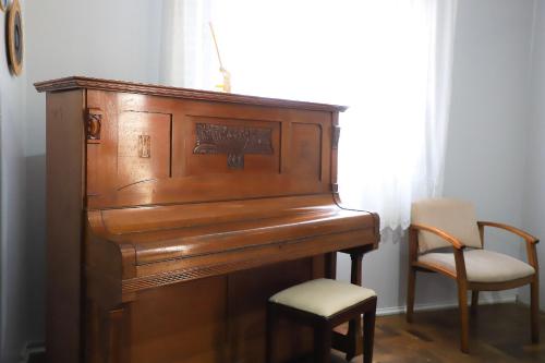 a wooden piano with a chair next to a window at Pousada Vista do Lago: Lazer e família em Gramado! in Gramado