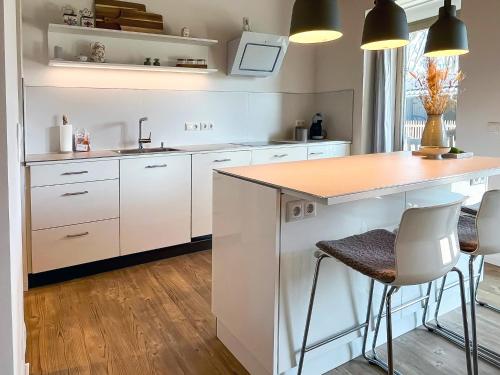 a kitchen with white cabinets and a island with stools at Landhaus Jarnitz in Ralswiek