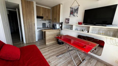 un salon avec une table rouge et une télévision dans l'établissement Le Modern & Mountain 2 étoiles, à Saint-Lary-Soulan