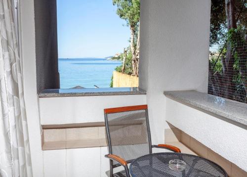 a table and chair on a balcony with a view of the ocean at Sunset Split Rooms in Podstrana